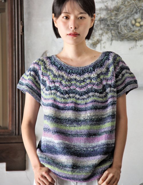 Woman wearing a colorful knitted shirt against a neutral background