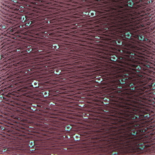 Close-up of a spool of red thread with small white flowers embedded in it.