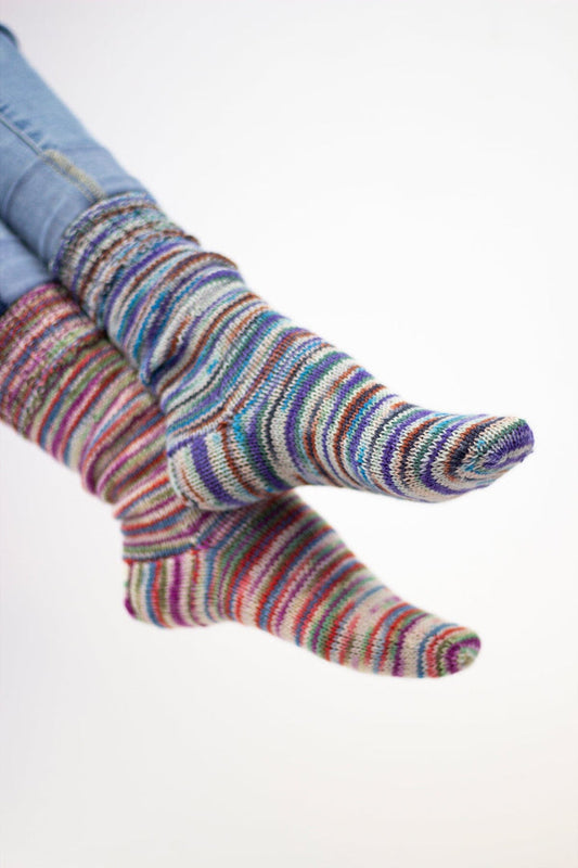 Multicolored striped socks worn with light blue jeans on a white background