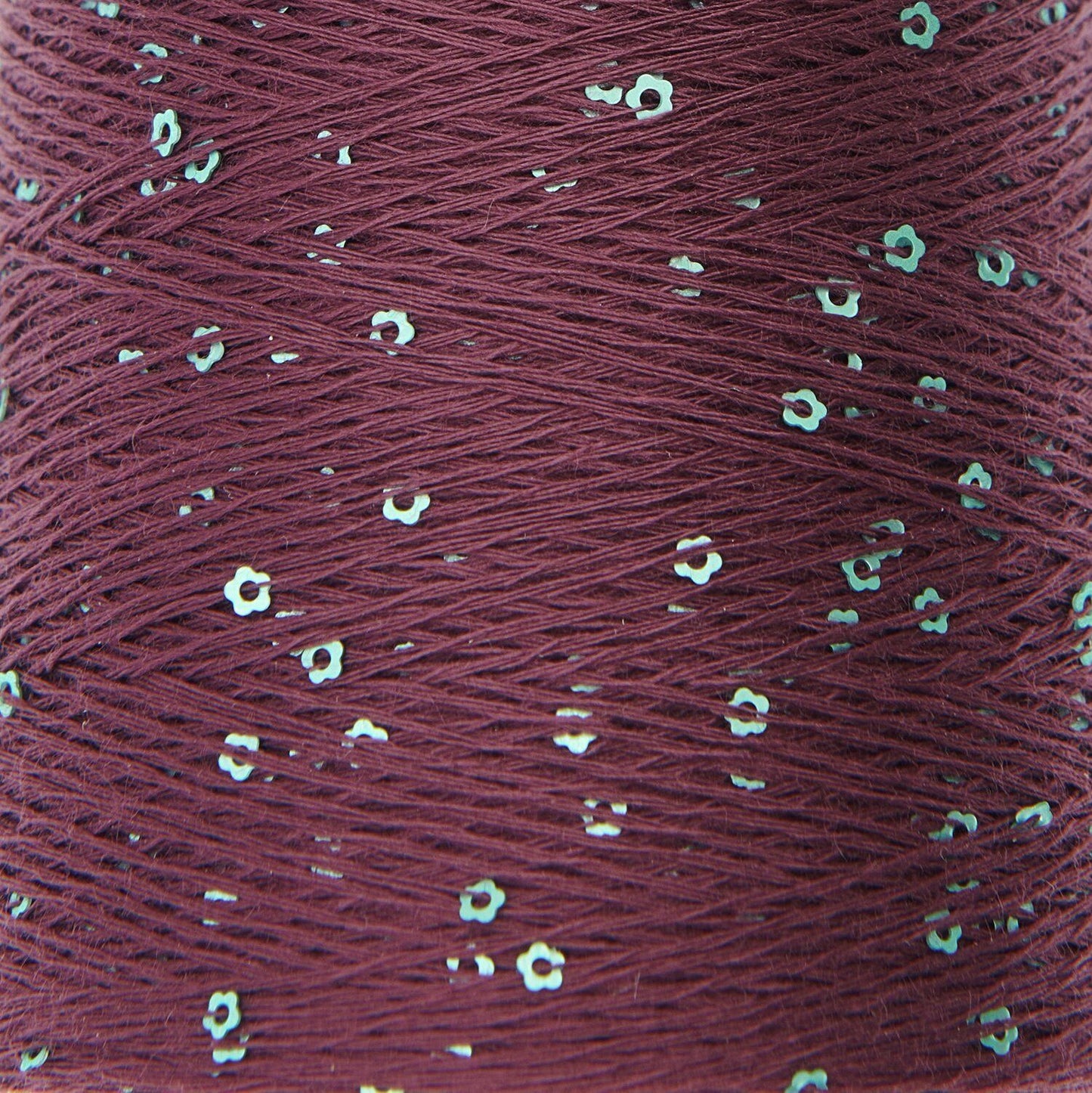 Close-up of a spool of red thread with small white flowers embedded in it.