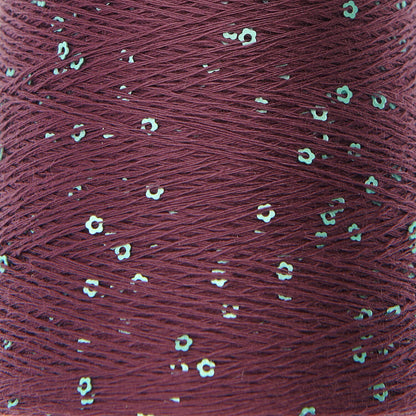 Close-up of a spool of red thread with small white flowers embedded in it.