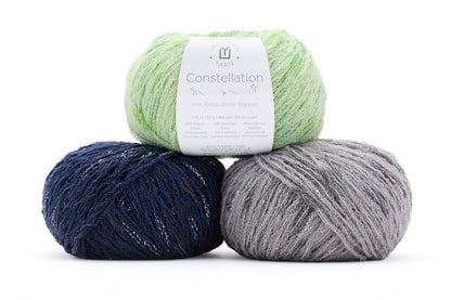 Three balls of yarn in green, blue, and gray with a label on a white background