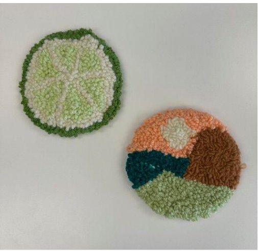 Two round textured coasters with green, white, orange, and brown patterns on a light gray background.