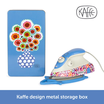 Kaffe design metal storage box with colorful floral design next to a polka dot iron on a white background.