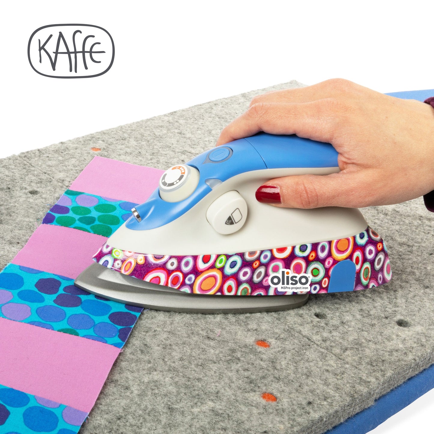 Colorful iron with Kaffe and Oliso branding on a quilt background