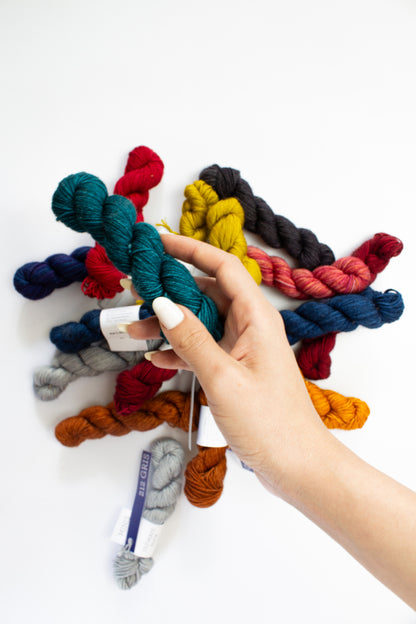 Hand holding a bundle of colorful yarn skeins on a white background